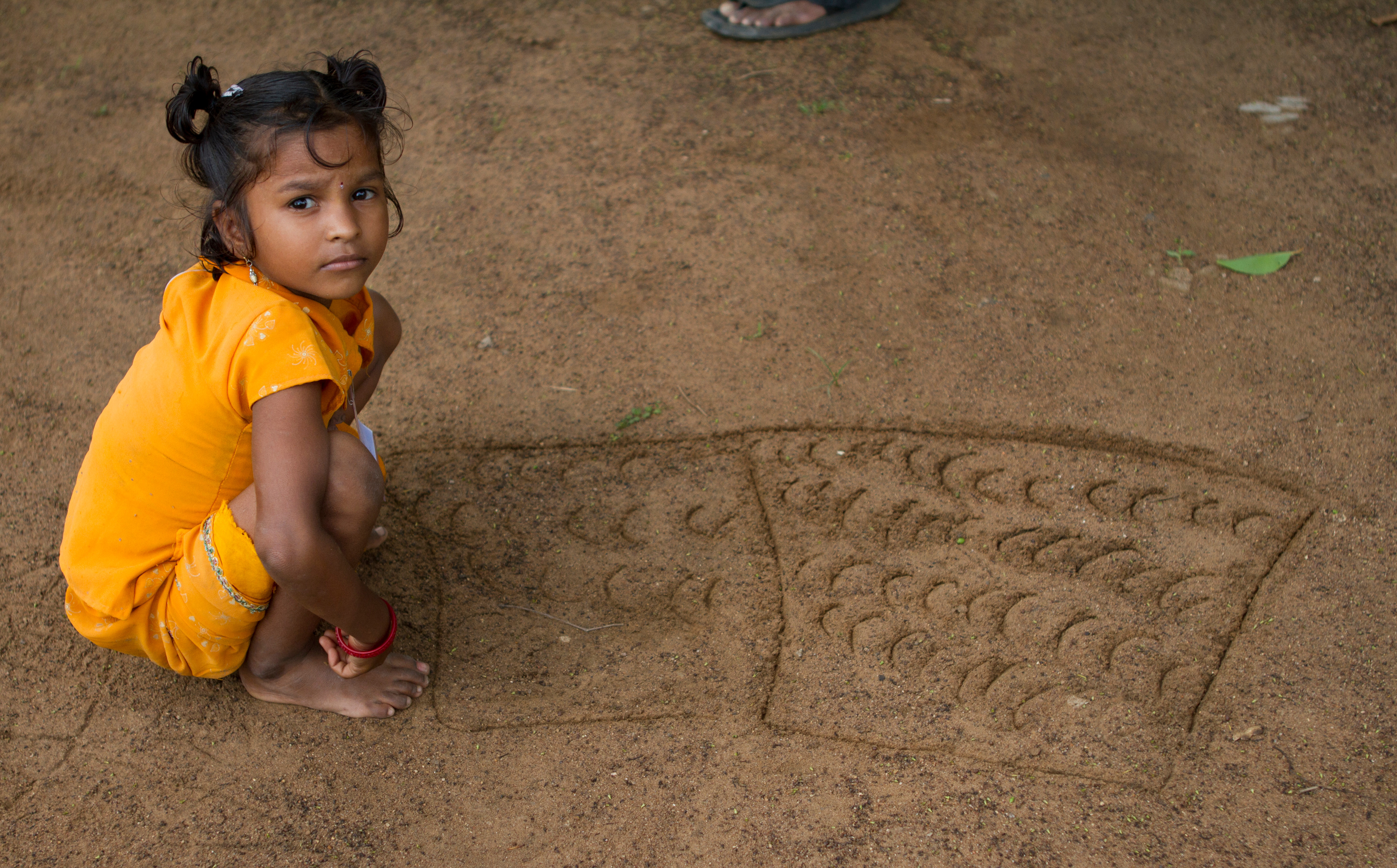 Little girl drawing in dirt