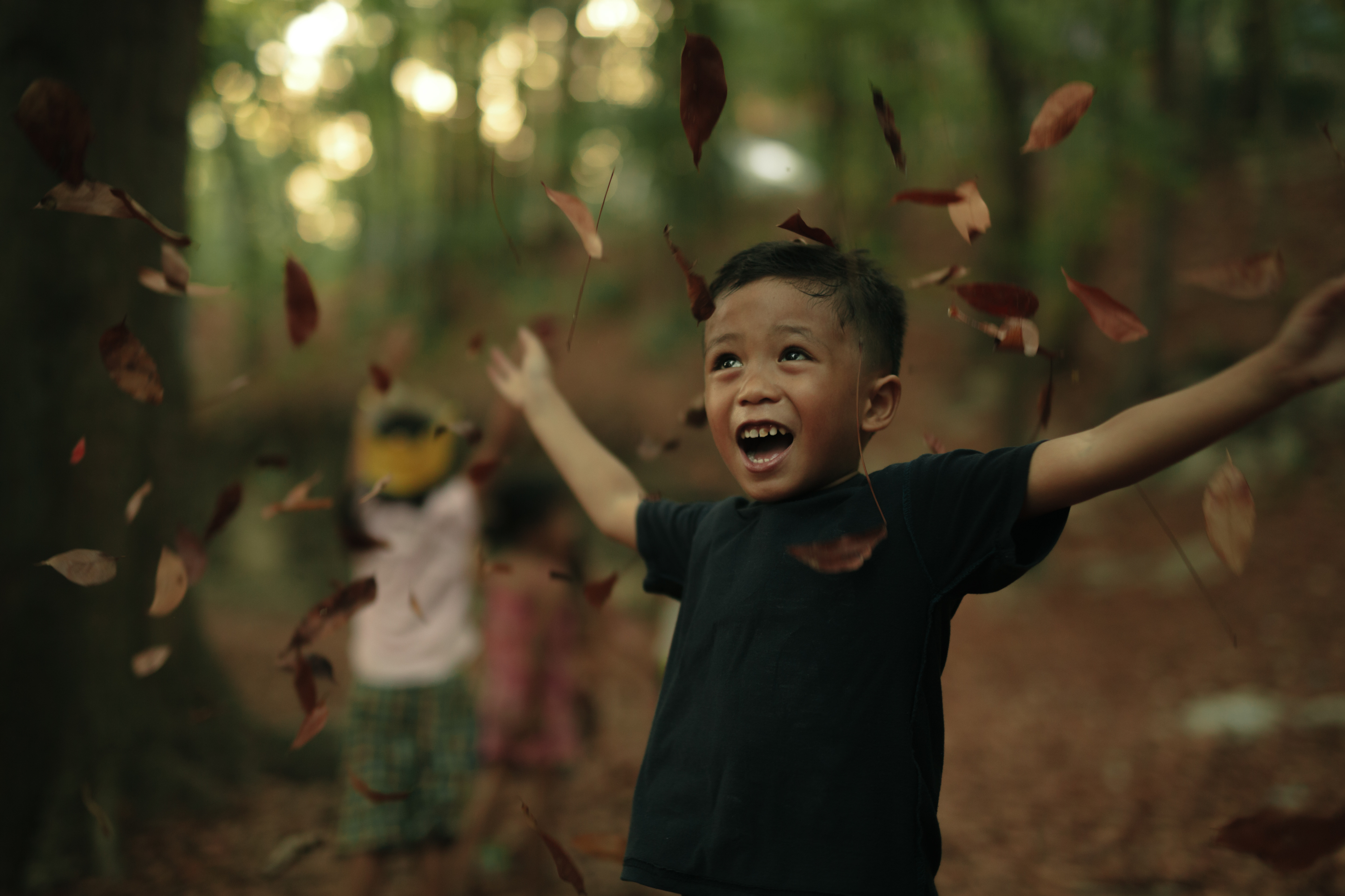 little boy throwing leaves and smiling